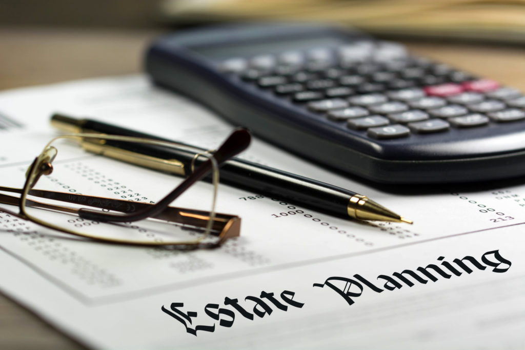 Calculadora, gafas y bolígrafo negro sobre documentos financieros de fondo, testamentos y herencias.