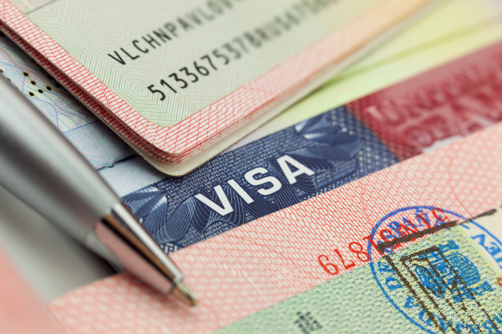Diferentes visados y sellos en un pasaporte - antecedentes de viaje, políticas de visados para inversores E-2, NDAA