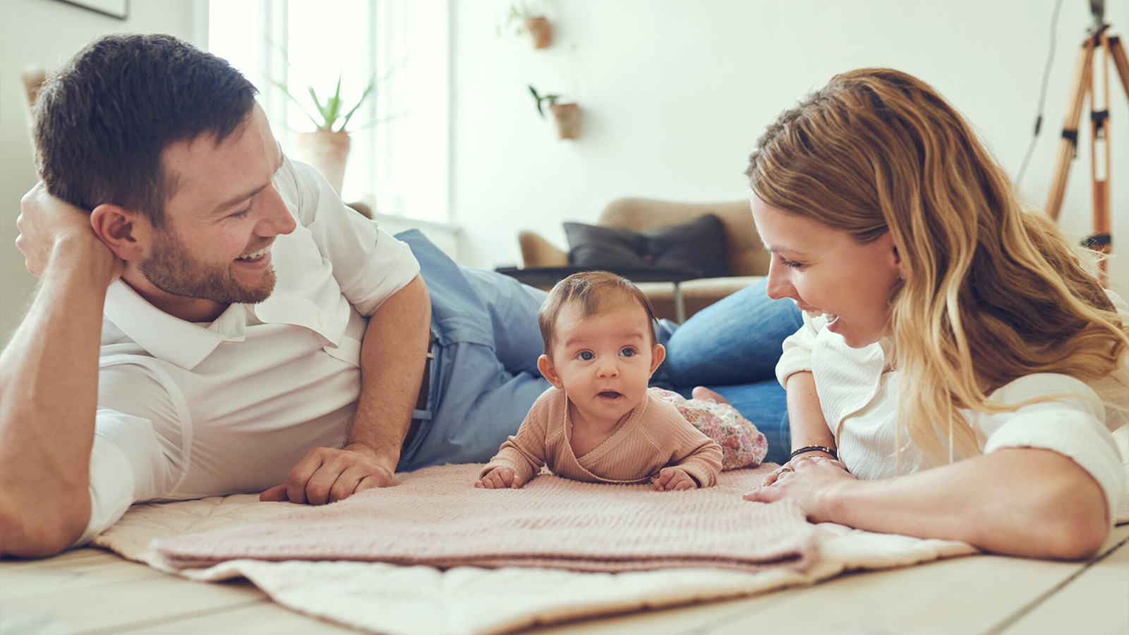 madre y padre jugando sobre una manta con un bebé, padres inmigrantes, ciudadanía