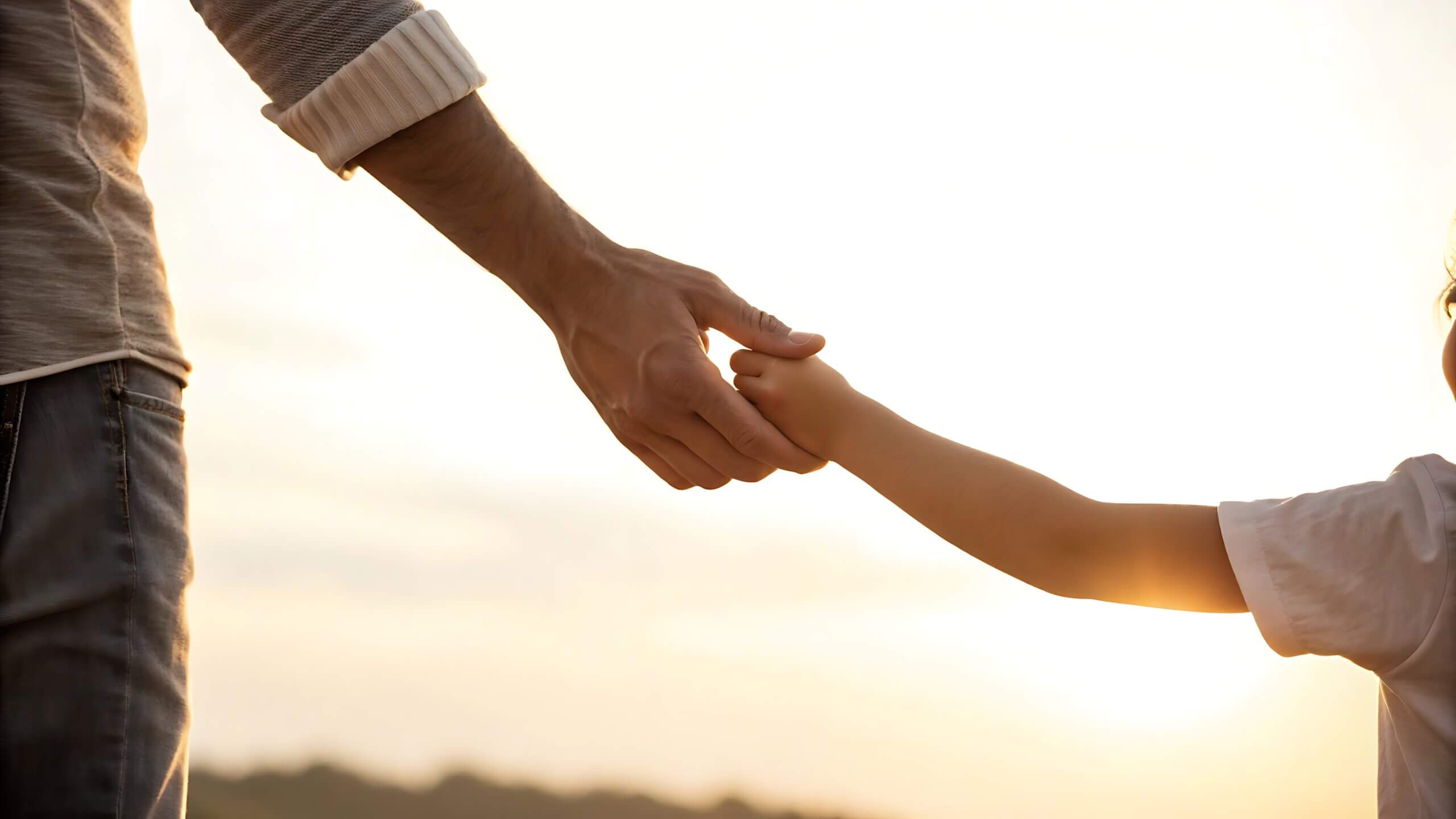 padre e hijo agarrados de la manos bajo el atardecer